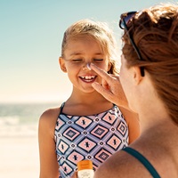 Mother uses Bambo Nature Sunscreen on child on beach
